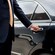 A private driver opening the door of a luxury sedan